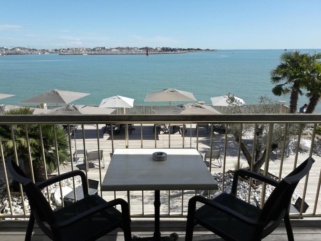 een tafel en stoelen op een balkon met uitzicht op het strand bij Hôtel Les Brises in La Rochelle