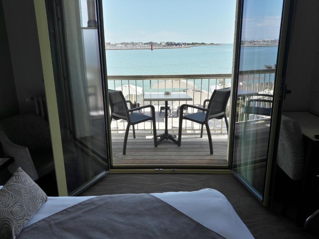 a bedroom with a balcony with a table and chairs at Hôtel Les Brises in La Rochelle
