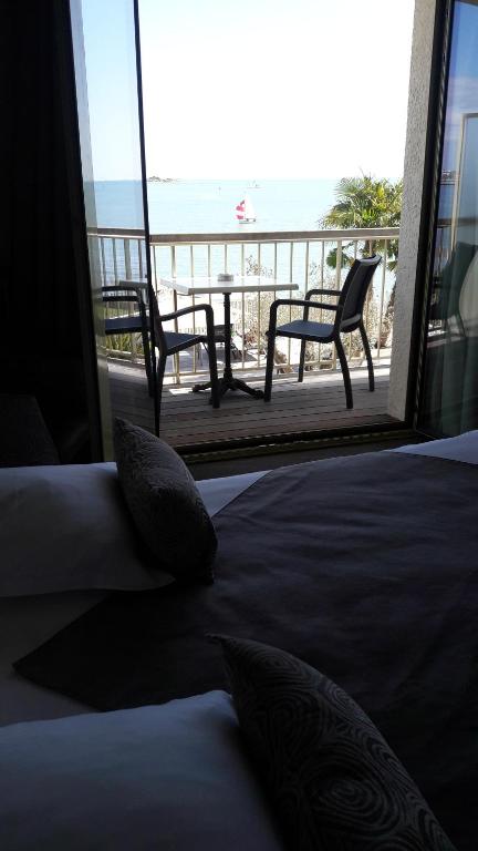a bedroom with a bed and a view of the beach at Hôtel Les Brises in La Rochelle