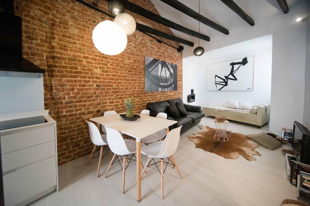 sala de estar con pared de ladrillo, mesa y sillas en Premium Piso Loft de 3 habitaciones en centro histórico, en Madrid