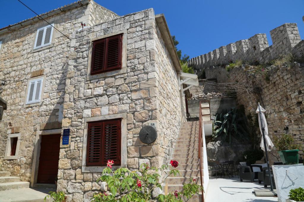 un antiguo edificio de piedra con persianas rojas. en Apartments Seka, en Hvar