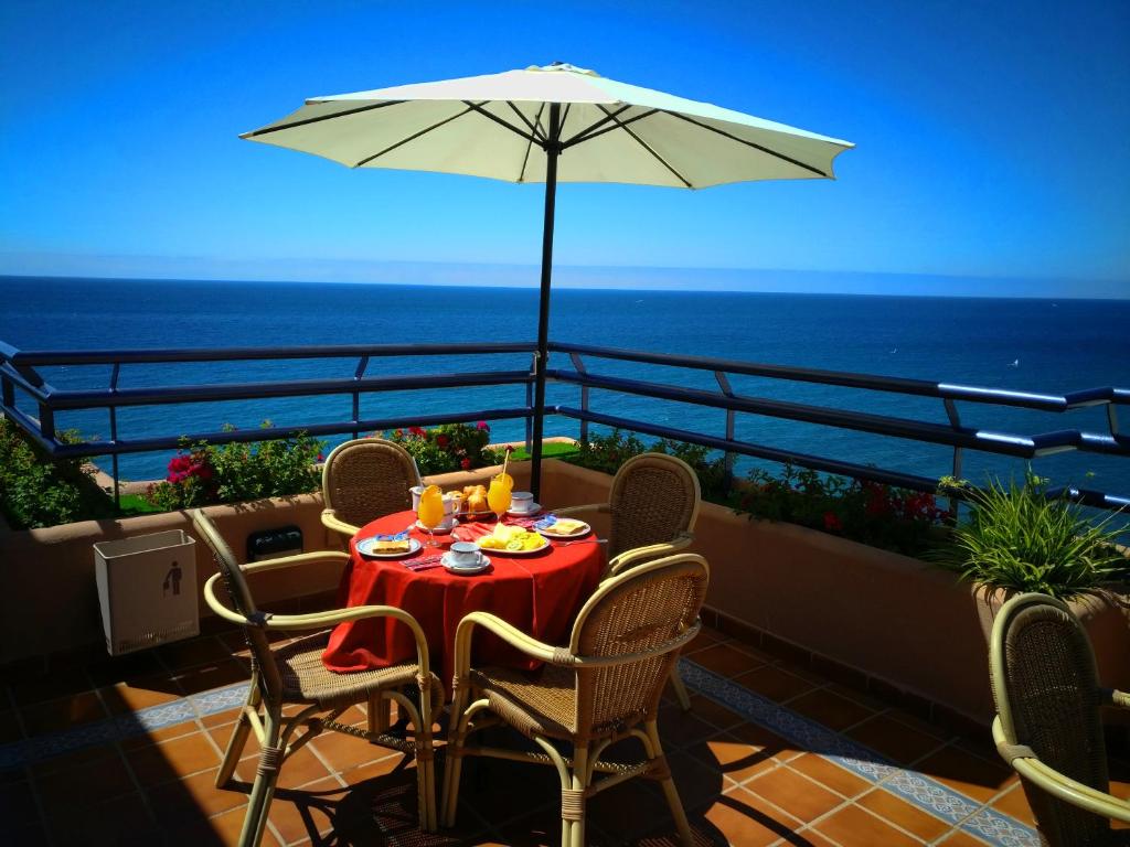 einen Tisch mit Stühlen und einem Sonnenschirm auf dem Balkon in der Unterkunft Hotel Apartamentos Princesa Playa in Marbella