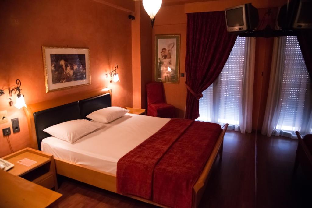 ピレウスにあるAlfa Hotelのベッドとテレビが備わるホテルルームです。
