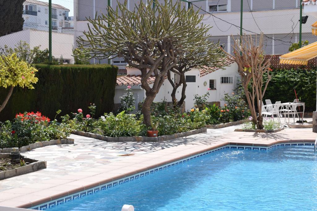 a swimming pool in a garden with trees and flowers at El Jardin BeNerja in Nerja