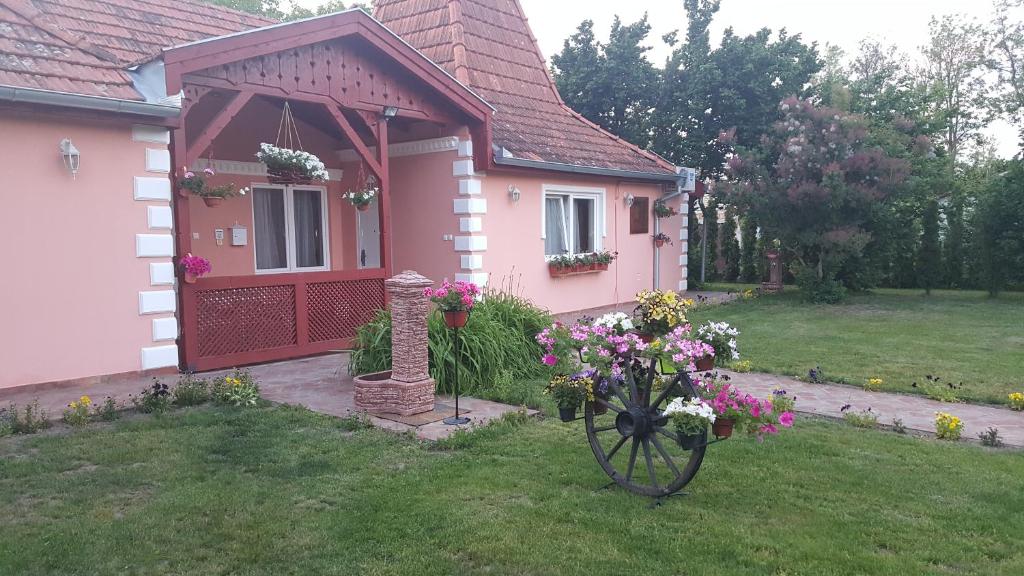 una casa rosa con una ruota piena di fiori in cortile di Villa Sunset a Palić