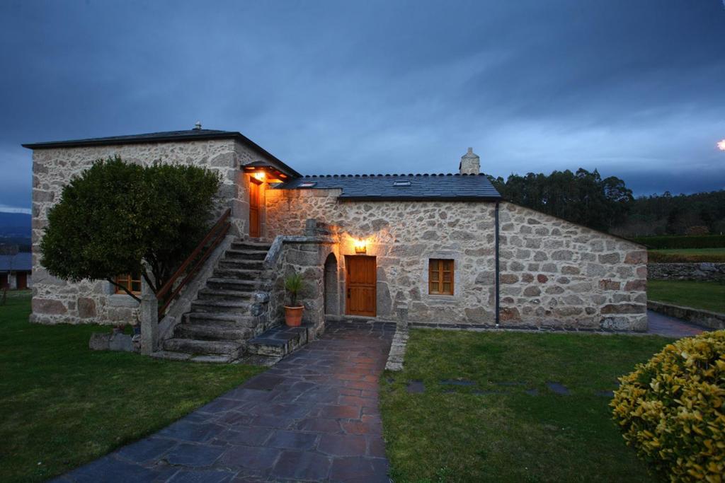 a stone house with a staircase leading up to it at Hotel Rústico Casa Franco in Adelán