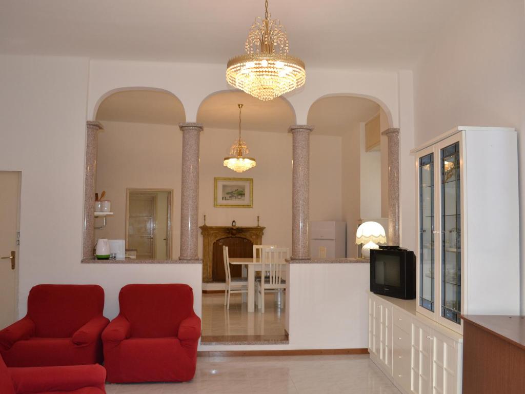 a living room with two red chairs and a tv at L'Antico Borgo in Lesa
