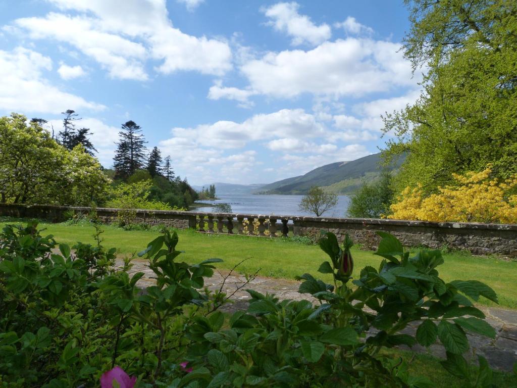 a view of a river with a stone wall and a lake at Butlers Quarters Apartment in Cairndow