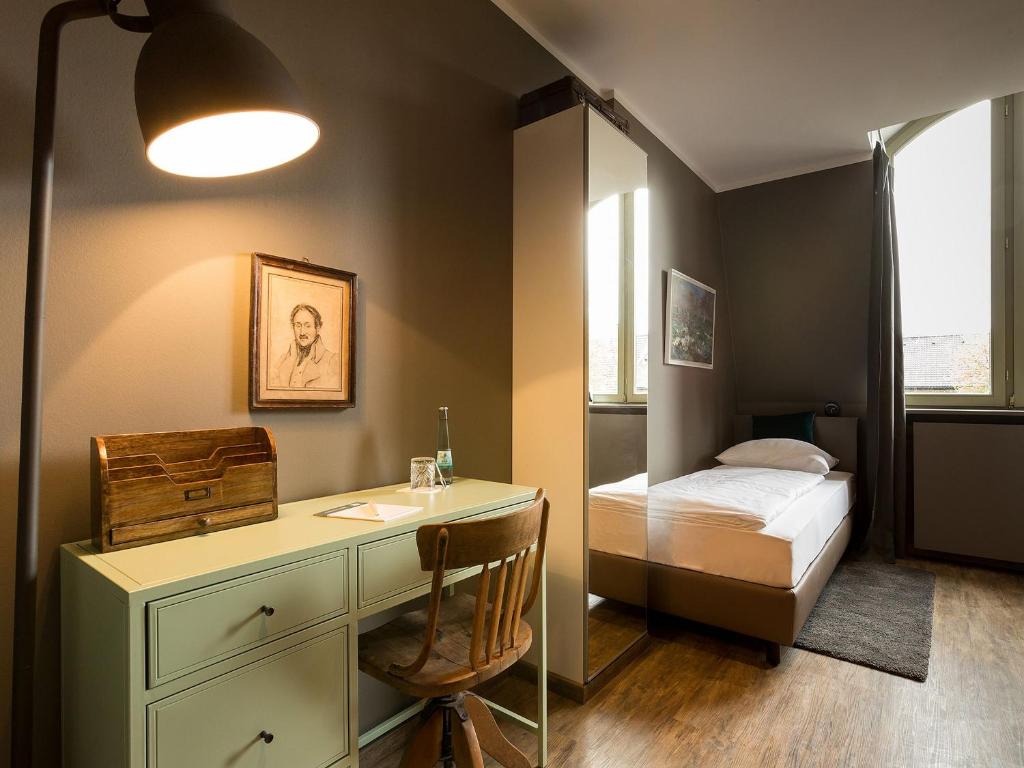 a bedroom with a desk and a bed in it at Hotel Heimathafen in Lörrach