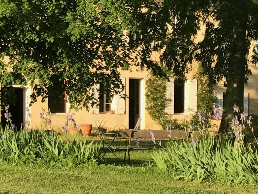 une maison blanche avec un banc dans l'herbe dans l'établissement B&B Château Pierre de Lune, à Saint-Émilion
