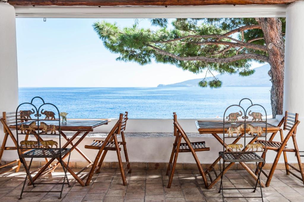 un patio con tavoli, sedie e vista sull'oceano di Hotel Mercanti di Mare a Santa Marina Salina