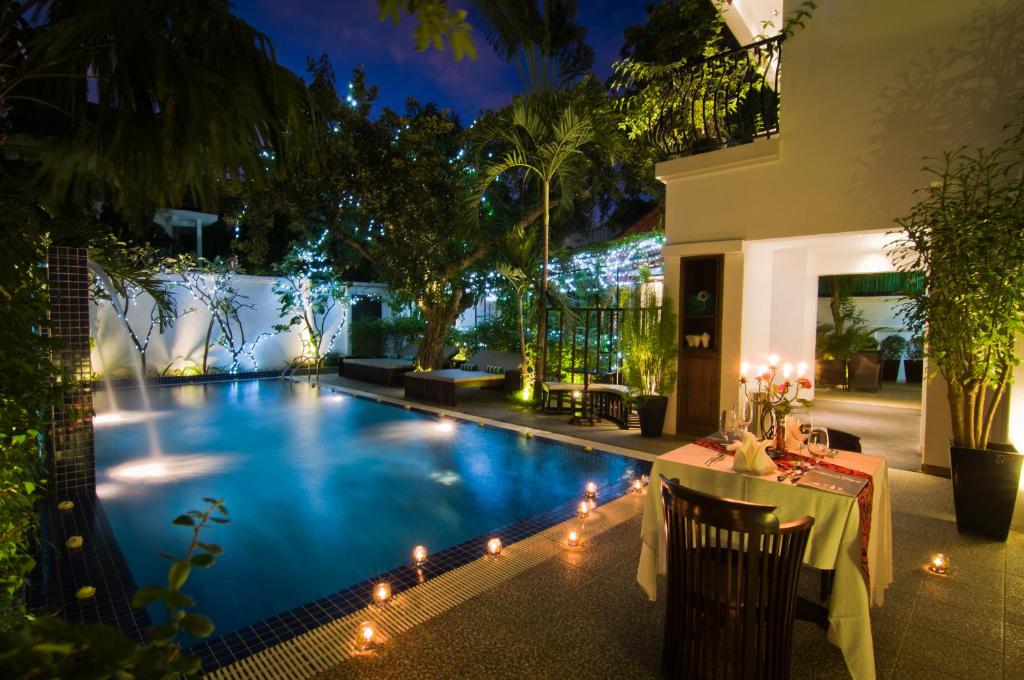 a swimming pool at night with a table and lights at La Rose Suites in Phnom Penh