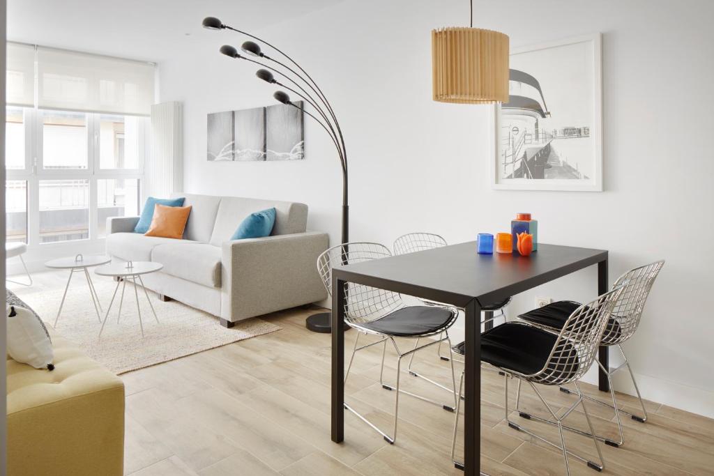 ein Wohnzimmer mit einem Tisch, Stühlen und einem Sofa in der Unterkunft Marina Suite by FeelFree Rentals in San Sebastián