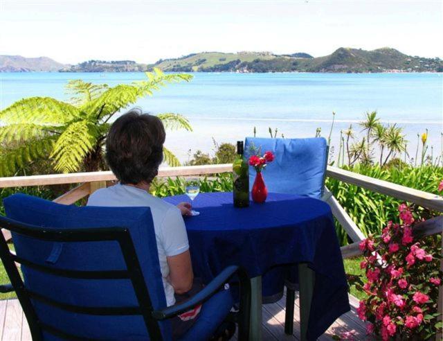 a woman sitting at a table with a view of the ocean at Harbour View Motel in Coromandel Town