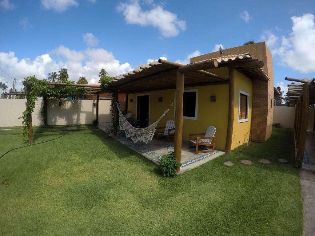 a house with a patio and a grass yard at Bangalô Patacho in Pôrto de Pedras