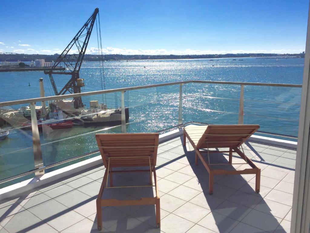 a balcony with two chairs and a view of the water at Princes Wharf 2BR Sub-Penthouse in Auckland