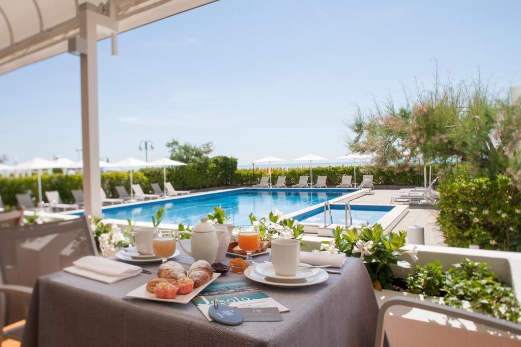 a table with food and drinks and a swimming pool at Hotel Imperial Palace in Lido di Jesolo