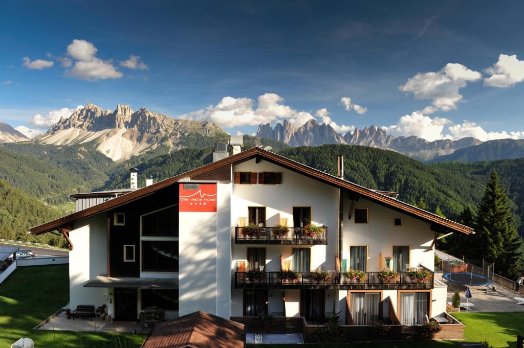 um edifício com varandas com montanhas ao fundo em The Vista Hotel em Bressanone