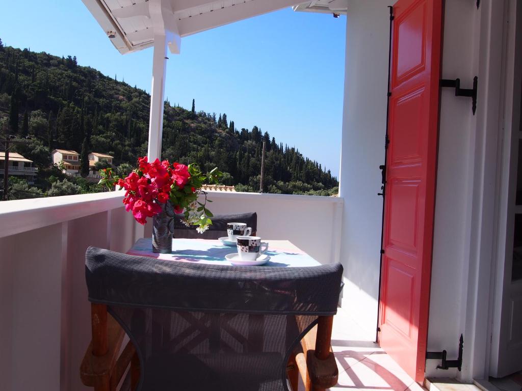 a table on a balcony with a vase of flowers at Eolos Apartments with Private Parking in Agios Nikitas