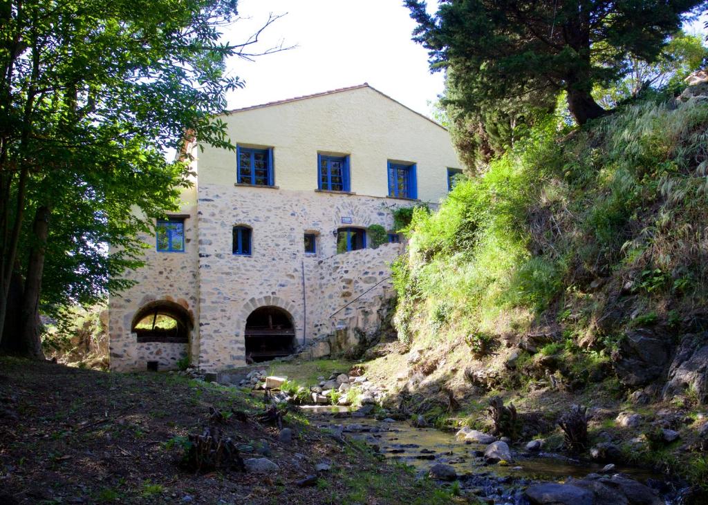 una vieja casa de piedra en una colina con un arroyo en Moulin de Perle, en Fosse