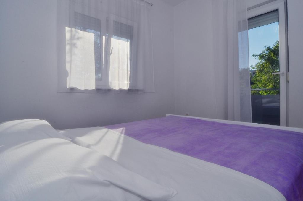 a white bedroom with a bed and a window at Apartments Edita in Zadar