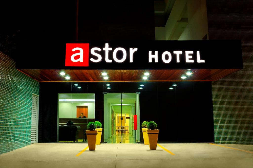 a star hotel with two potted plants in front of it at Astor Hotel in Bauru