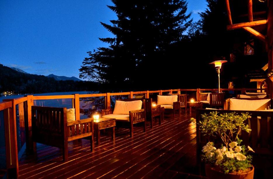 a deck with chairs and a table and lights at Dos Bahias Lake Resort in Villa La Angostura