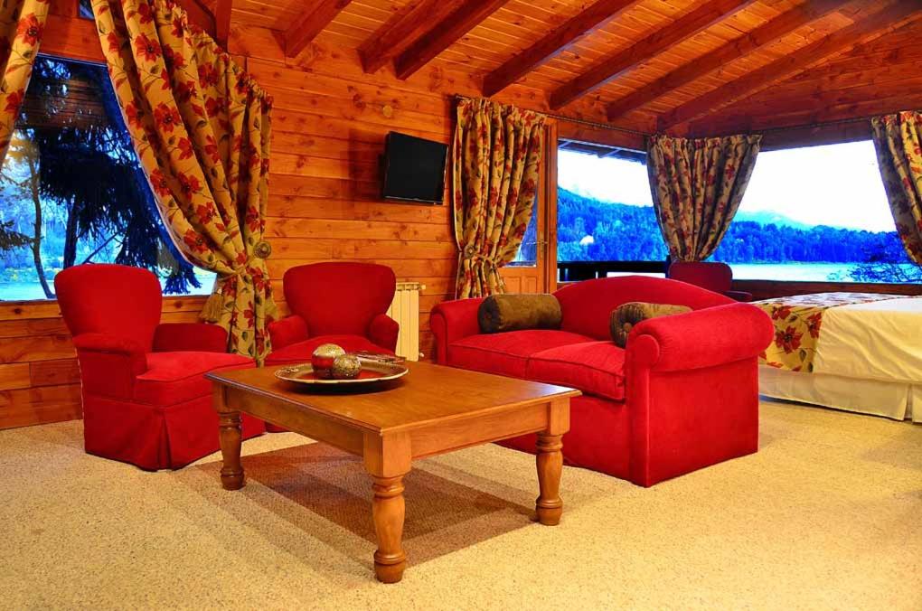 a living room with two red chairs and a table at Dos Bahias Lake Resort in Villa La Angostura