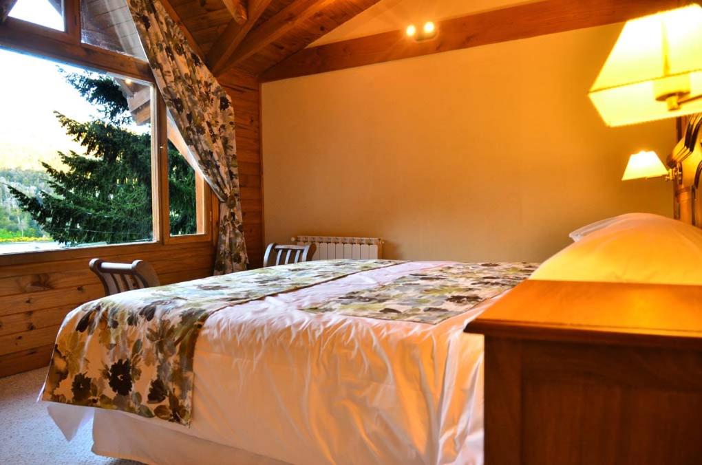 a bedroom with a bed and a large window at Dos Bahias Lake Resort in Villa La Angostura