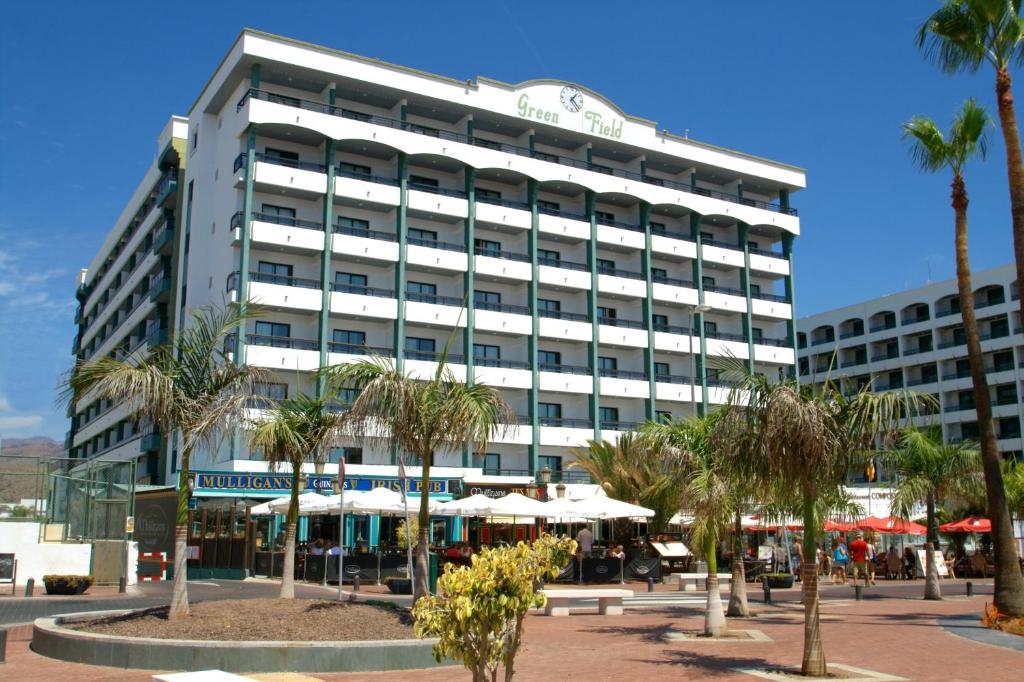 un gran edificio blanco con palmeras delante en Hotel Green Field, en Playa del Inglés