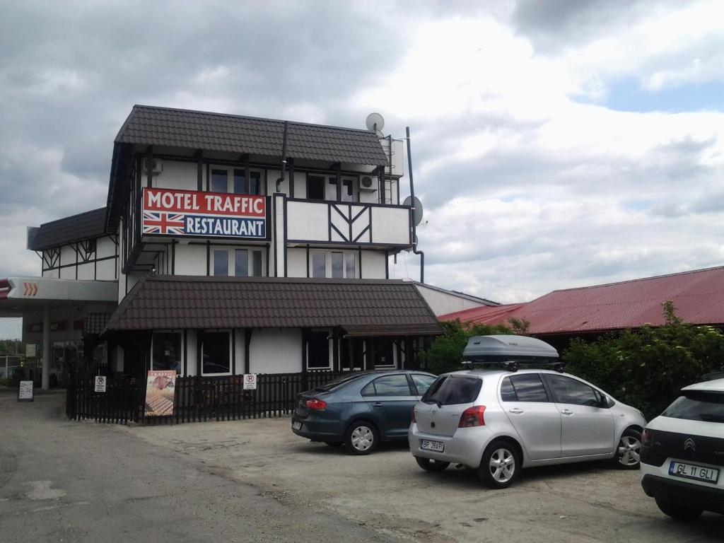 dos autos estacionados en un estacionamiento frente a un edificio en Motel Traffic, en Linteşti