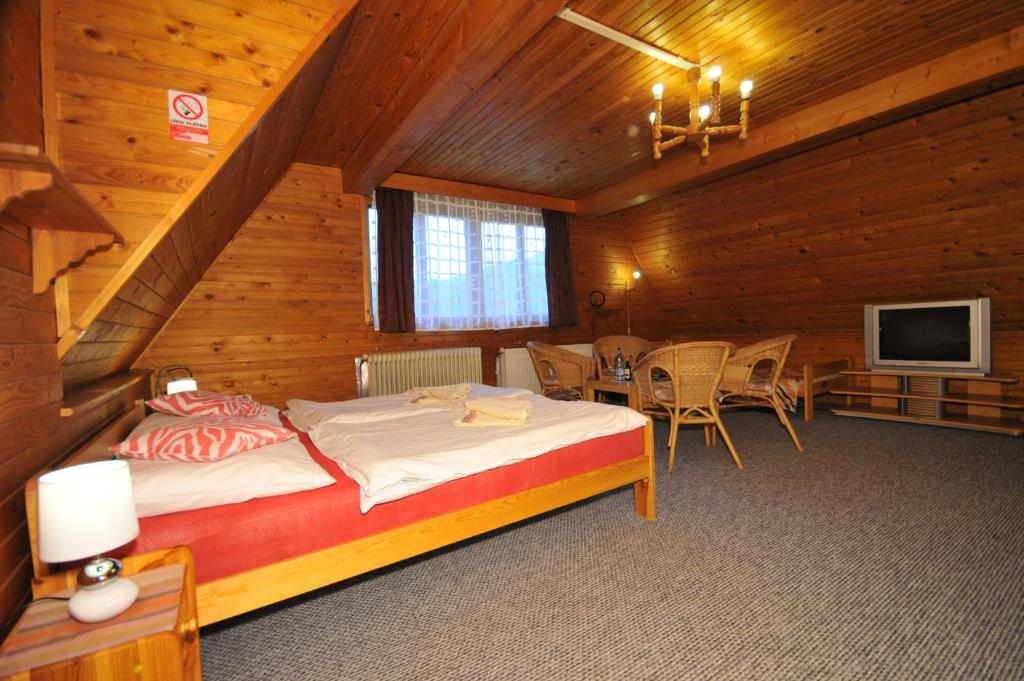 um quarto com uma cama, uma mesa e uma televisão em Penzión Pastierňa em Dedinky