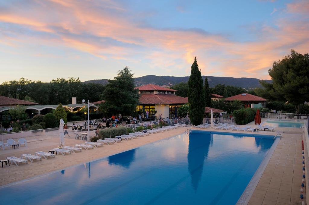een groot zwembad met stoelen en een resort bij Village Vacances La Manne in Bormes-les-Mimosas