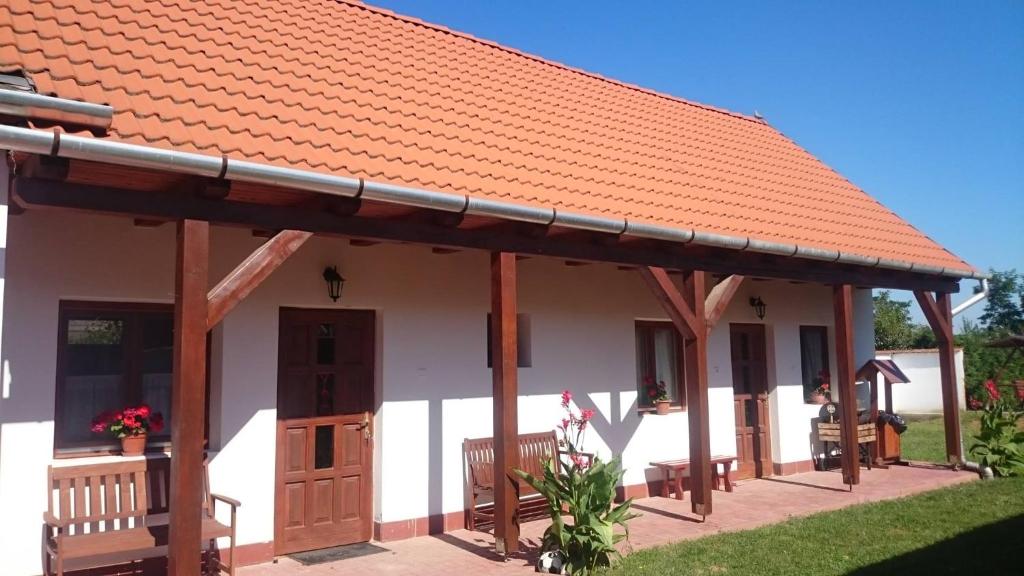a small white house with an orange roof at Szenkeparti Vendégház in Penyige