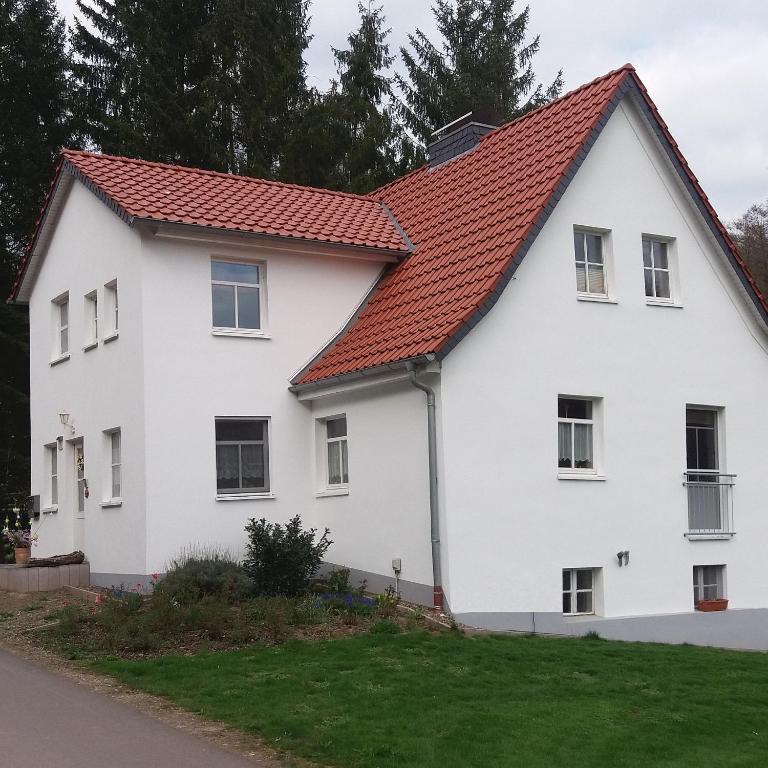 a white house with a red roof at Apartment am Golfplatz in Brochthausen