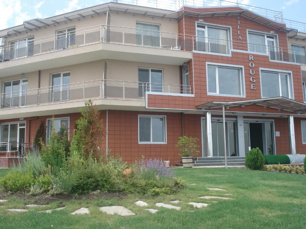 een rood bakstenen gebouw met een gazon ervoor bij Villa Rouge in Sozopol