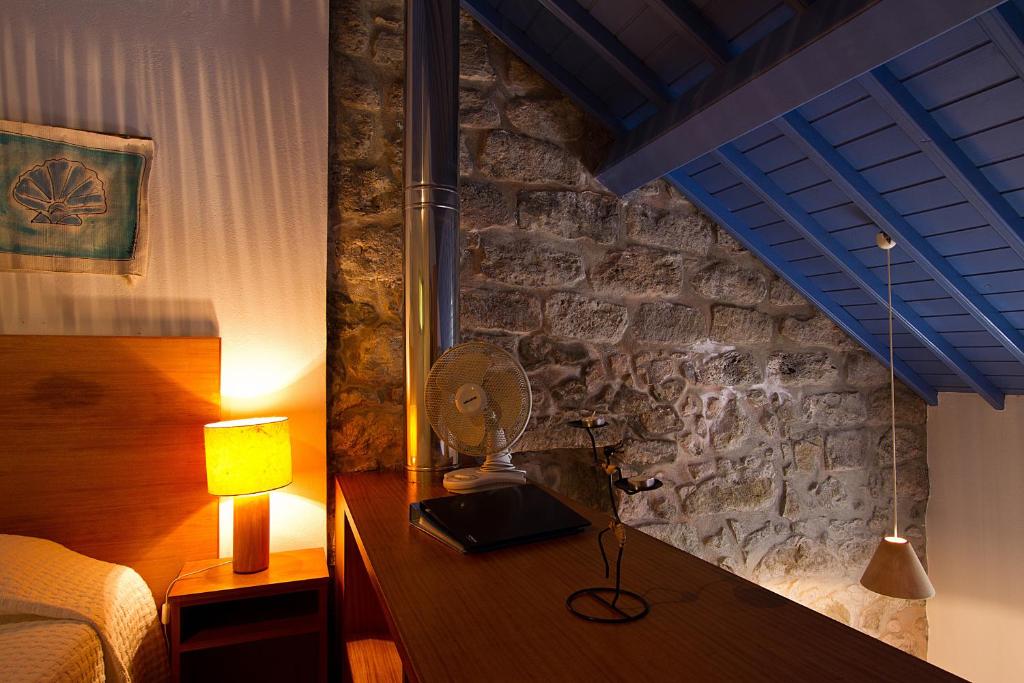 a bedroom with a bed and a desk with a lamp at Casa de Pedra in Ribeira Quente