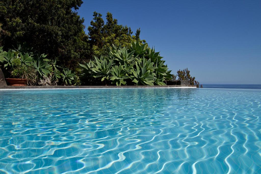 a pool of blue water with trees in the background at Casa de Pedra in Ribeira Quente