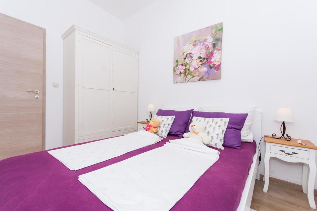 a bedroom with two beds with purple and white at Lavanda in Kaštela