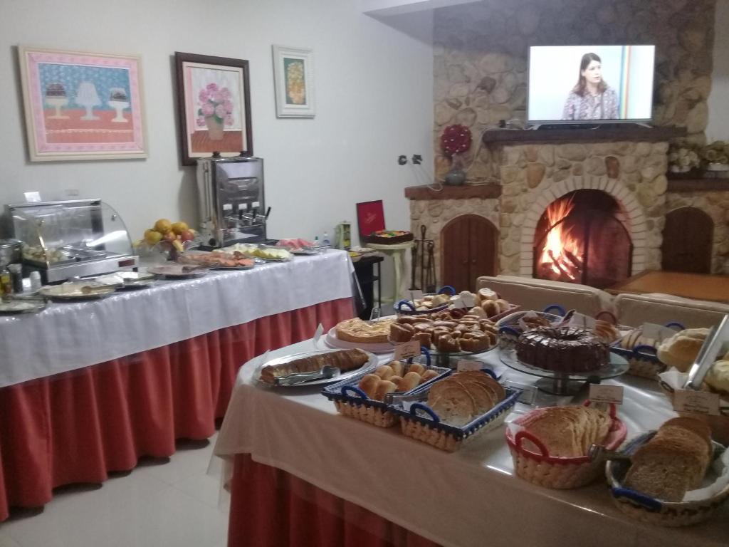 a group of tables with food and a fireplace at Pousada Doce Vida in Campos do Jordão