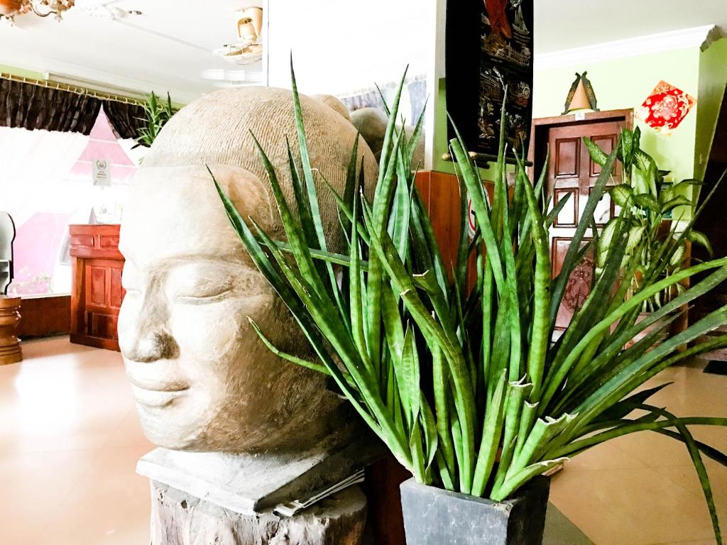 a statue of a head sitting next to a plant at Ta Som Guesthouse & Tour Services in Siem Reap