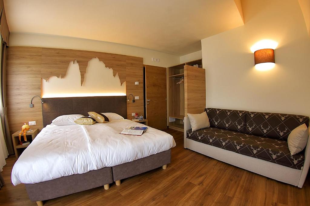 ヴァッターロにあるBotton d'Oro delle Dolomitiのベッドルーム(大型ベッド1台、ソファ付)