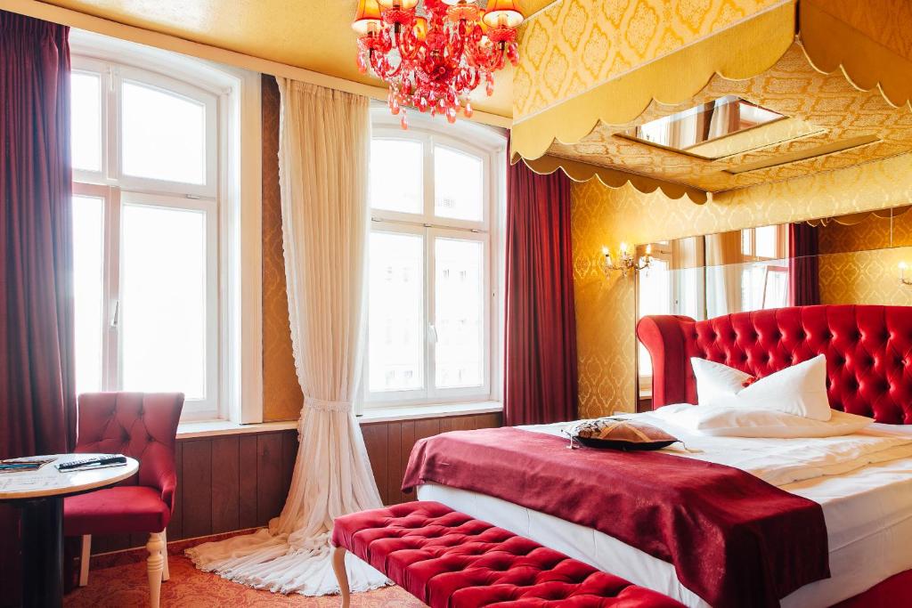 a bedroom with a red bed and a chandelier at Hotel Village in Hamburg