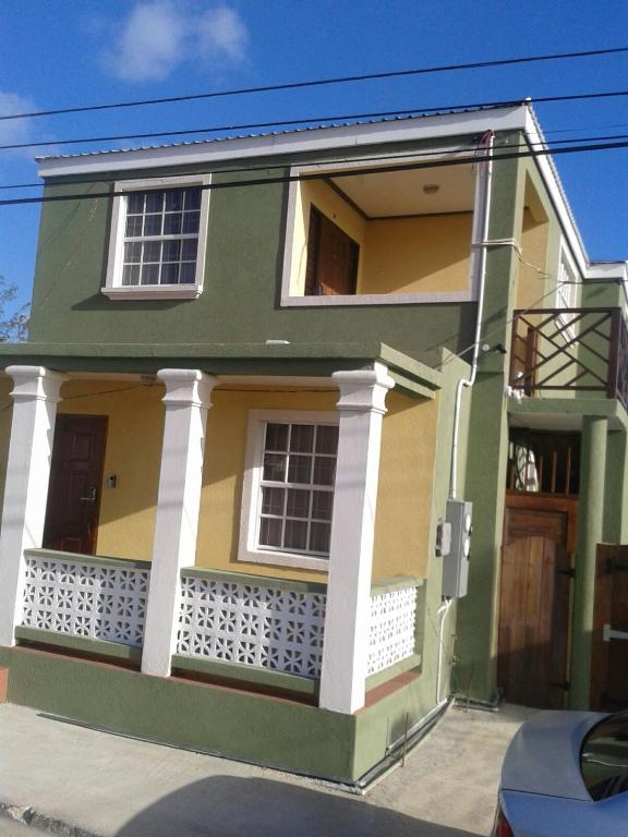 a green and yellow house with a balcony at Believe Caribbean Apartment in Bridgetown