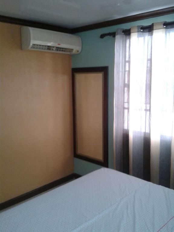 a bedroom with a bed and a window and a fan at Believe Caribbean Apartment in Bridgetown