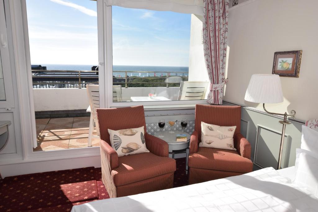 a bedroom with a bed and two chairs and a window at Hotel Wiking Sylt in Westerland (Sylt)
