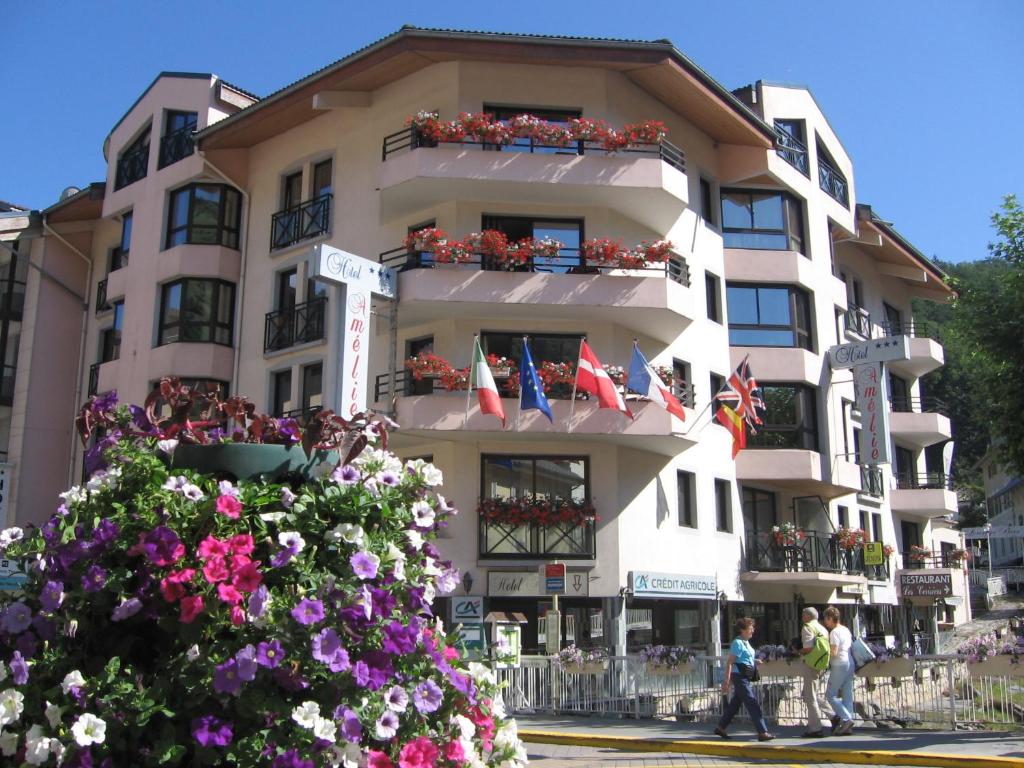 un edificio blanco alto con flores delante en Hotel Amélie en Brides-les-Bains