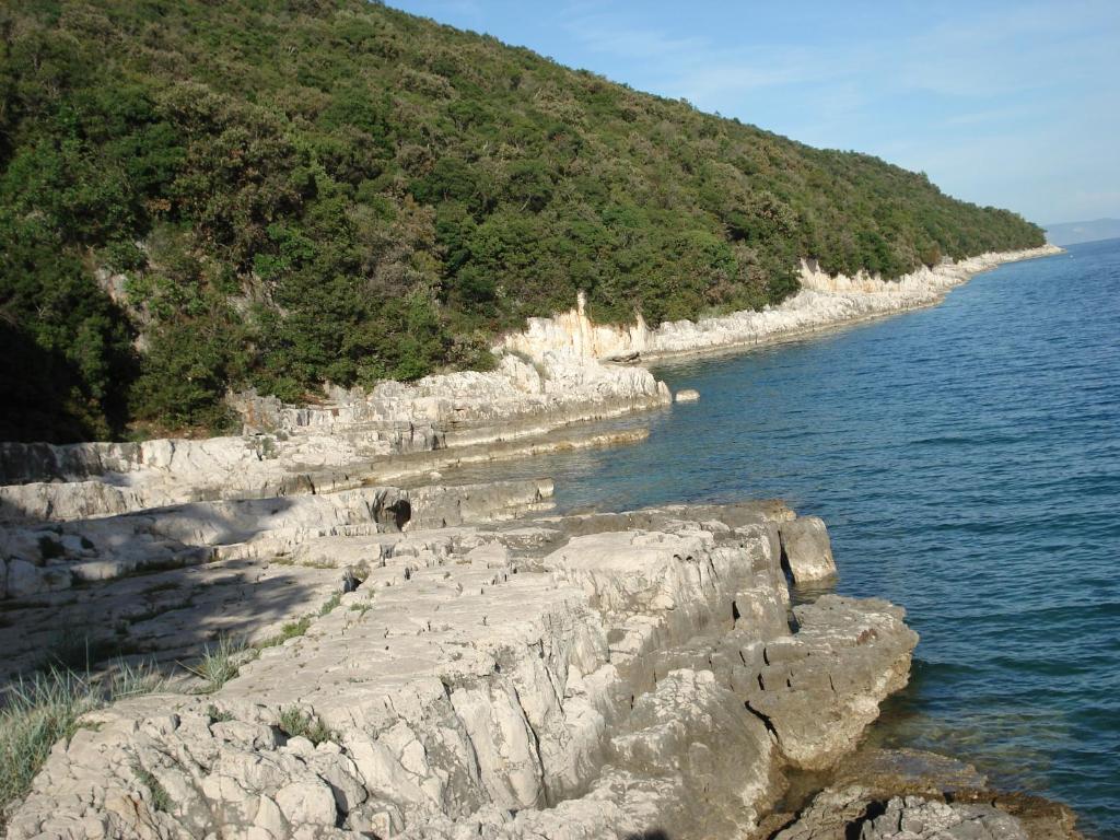 a group of people walking along a rocky shore at Apartmani Tijano in Krnica