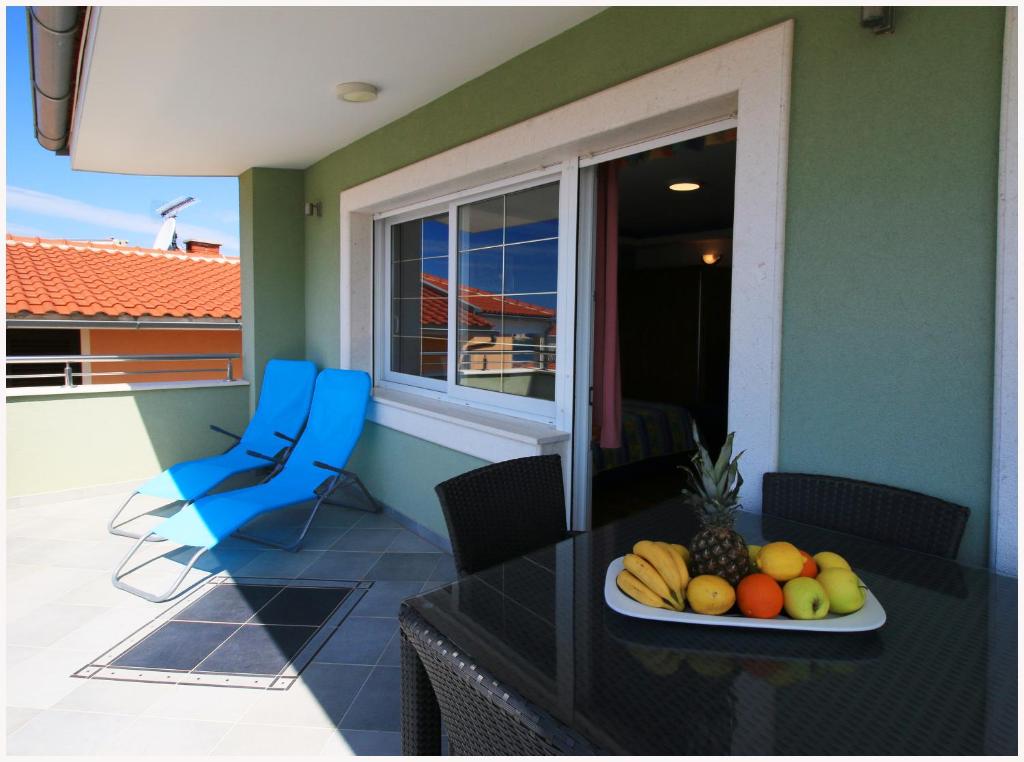a plate of fruit on a table on a balcony at Apartmani- Šjor -Primošten-Apartmani- has 2 large apartments and 2 smaller ones -Primošten Lokvice 6 in Primošten