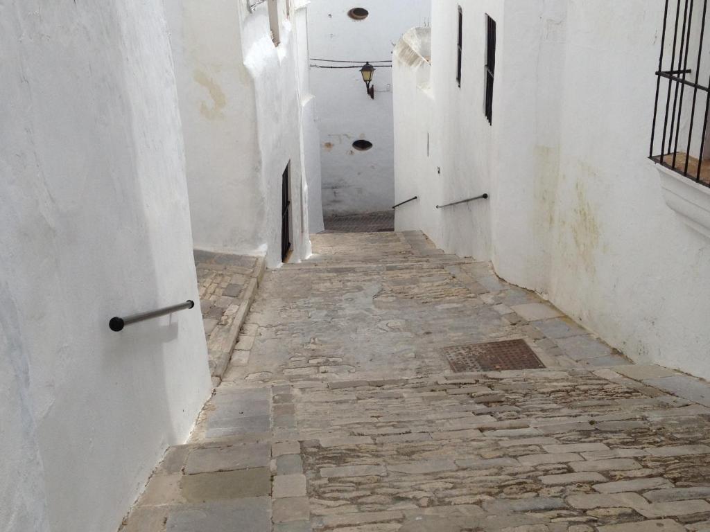 an alley way with white walls and a stone floor at Apartamentos Casa la Costanilla in Vejer de la Frontera